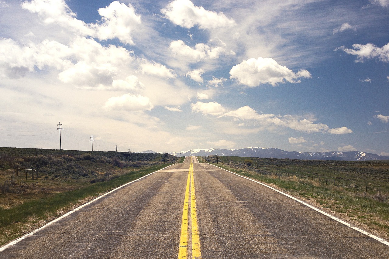 Long straight road with double yellow lines in the middle, stretching out into the distance through barren, flat land